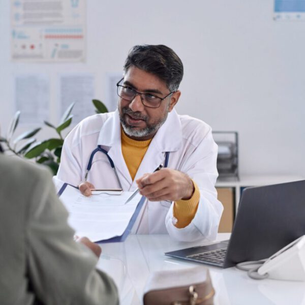 Portrait of senior bearded doctor handing clipboard to female patient across table copy space